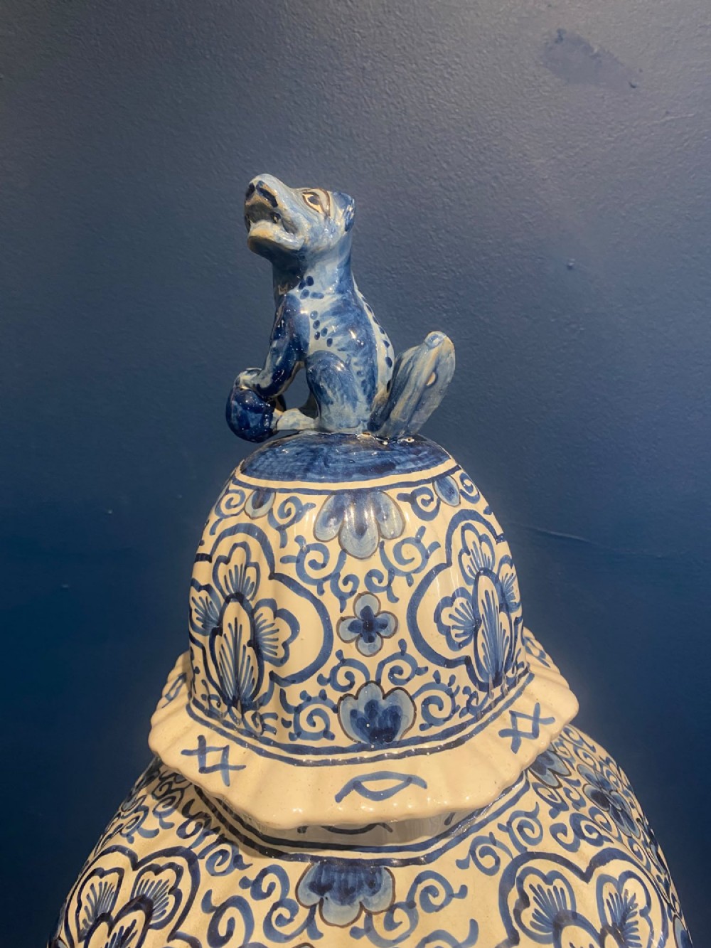 A pair of mid-19th century ribbed blue and white tin-glazed earthenware lidded vases hand-painted with oriental landscapes and topped with seated lion finials. View VII