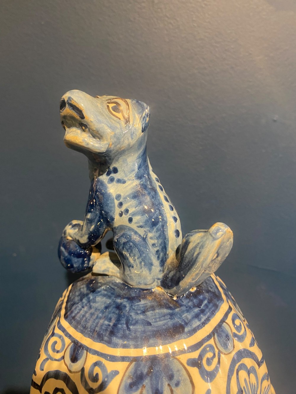 A pair of mid-19th century ribbed blue and white tin-glazed earthenware lidded vases hand-painted with oriental landscapes and topped with seated lion finials. View VIII
