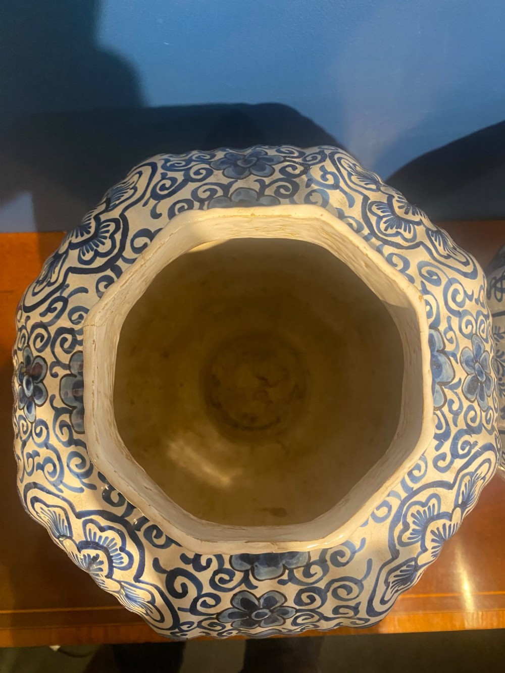A pair of mid-19th century ribbed blue and white tin-glazed earthenware lidded vases hand-painted with oriental landscapes and topped with seated lion finials. View X