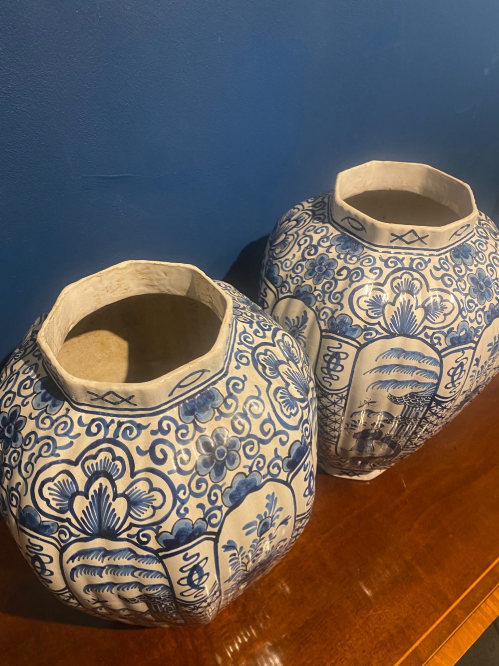 A pair of mid-19th century ribbed blue and white tin-glazed earthenware lidded vases hand-painted with oriental landscapes and topped with seated lion finials. View XI