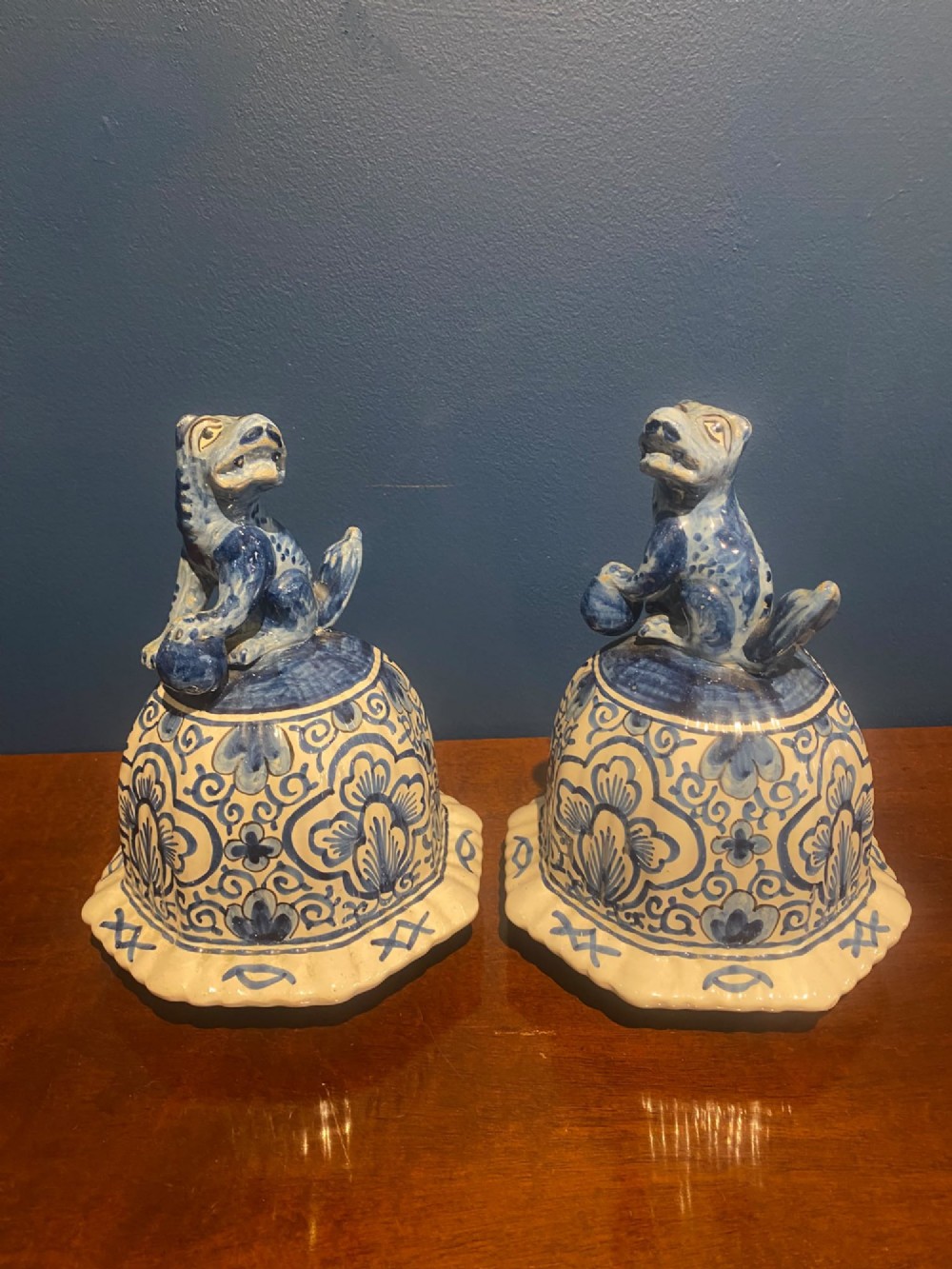 A pair of mid-19th century ribbed blue and white tin-glazed earthenware lidded vases hand-painted with oriental landscapes and topped with seated lion finials. View XII