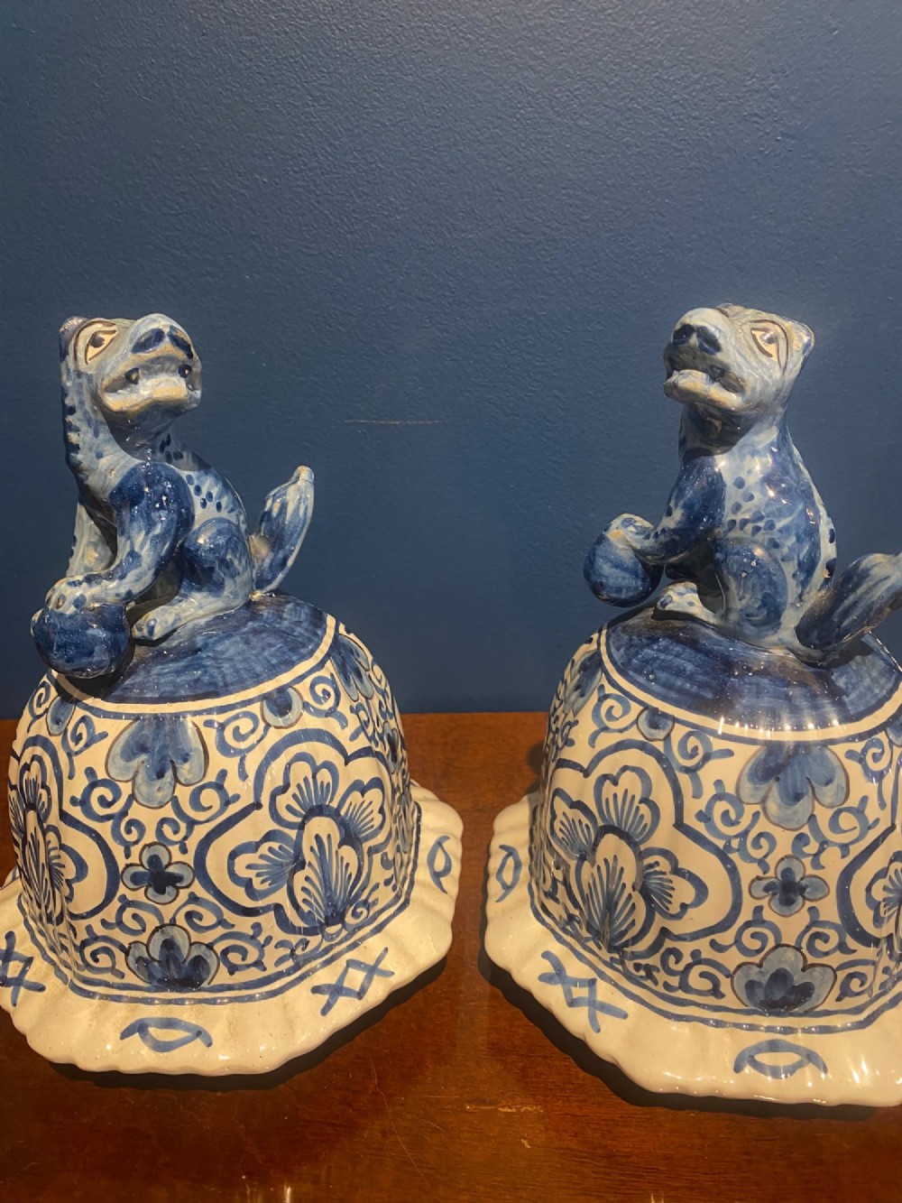 A pair of mid-19th century ribbed blue and white tin-glazed earthenware lidded vases hand-painted with oriental landscapes and topped with seated lion finials. View XIII