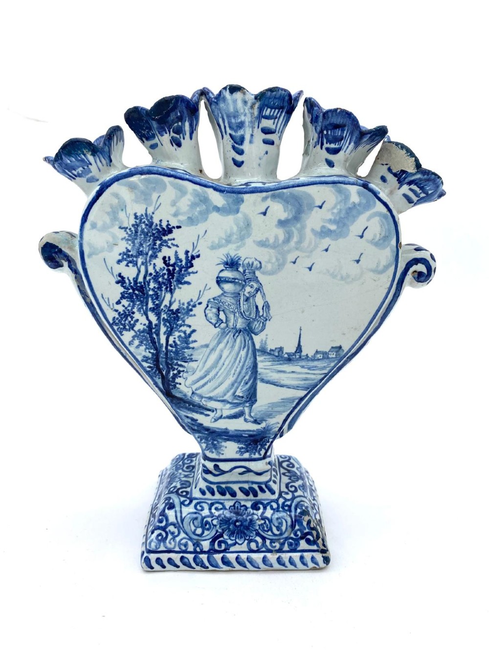 A pair of blue and white heart-shaped ceramic tulipieres featuring multiple spouts and hand-painted Dutch figures in landscape settings. View III