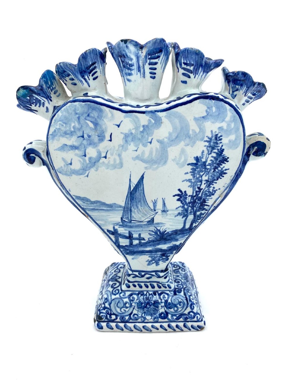 A pair of blue and white heart-shaped ceramic tulipieres featuring multiple spouts and hand-painted Dutch figures in landscape settings. View IV