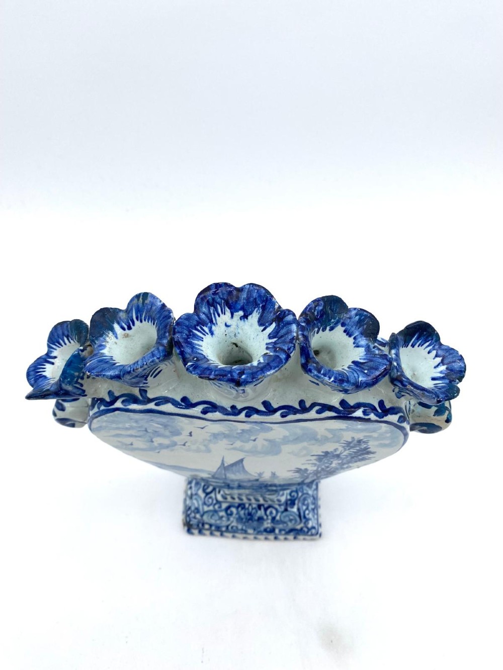 A pair of blue and white heart-shaped ceramic tulipieres featuring multiple spouts and hand-painted Dutch figures in landscape settings. View V