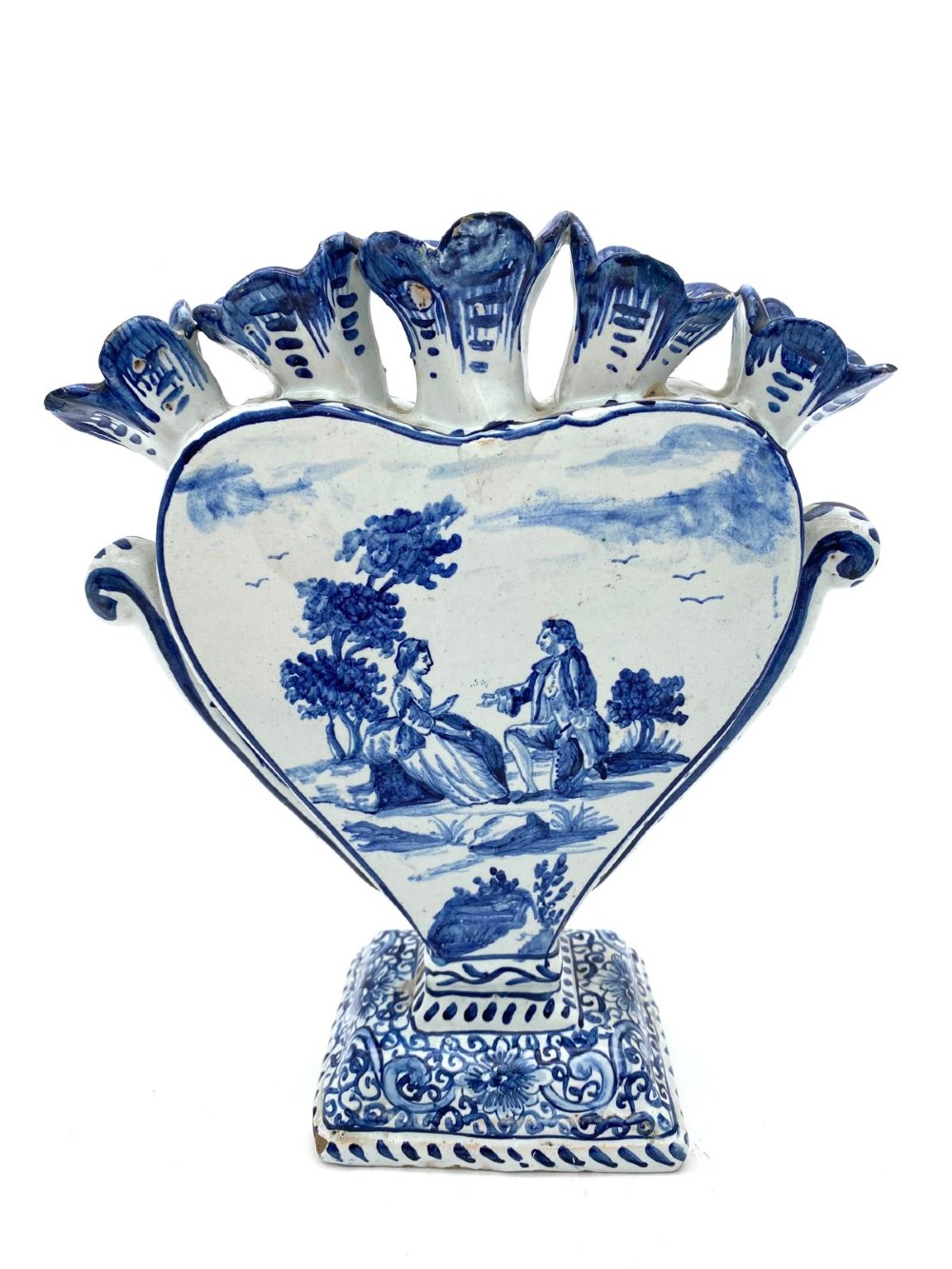 A pair of blue and white heart-shaped ceramic tulipieres featuring multiple spouts and hand-painted Dutch figures in landscape settings. View IX