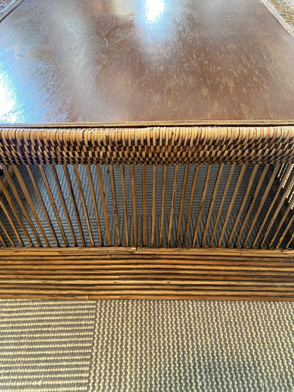A rectangular warm brown wooden coffee table featuring a recessed top panel surrounded by woven rattan borders and vertical reed slatted sides. View VII