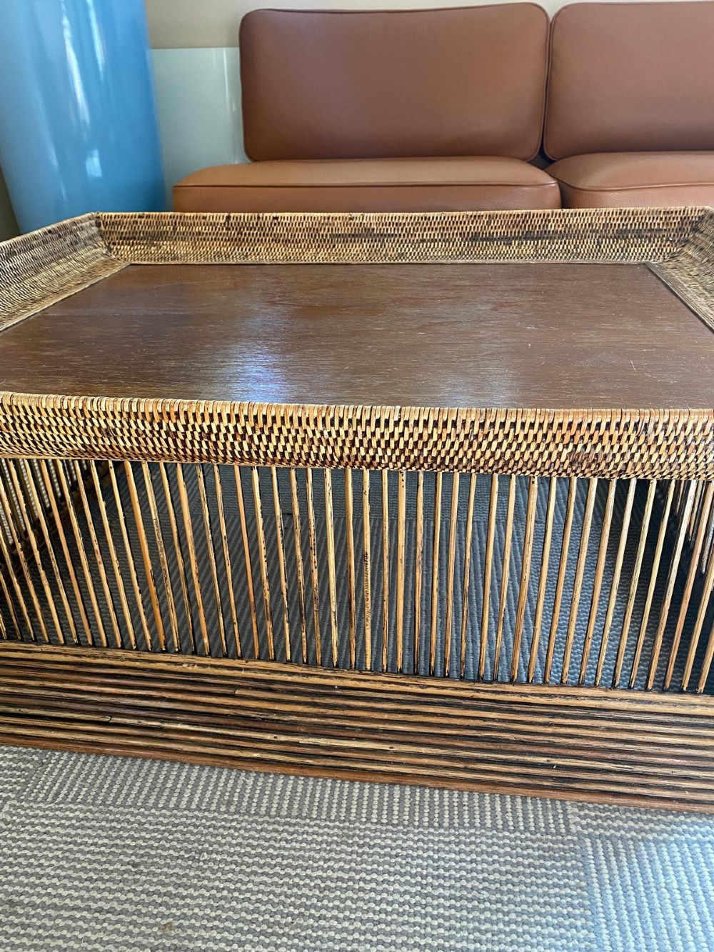 A rectangular warm brown wooden coffee table featuring a recessed top panel surrounded by woven rattan borders and vertical reed slatted sides. View IX