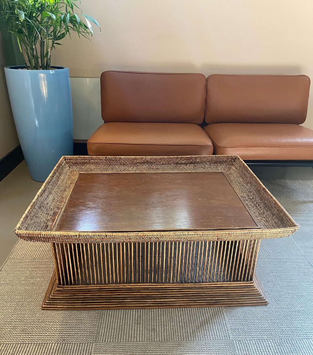 A rectangular warm brown wooden coffee table featuring a recessed top panel surrounded by woven rattan borders and vertical reed slatted sides. View X