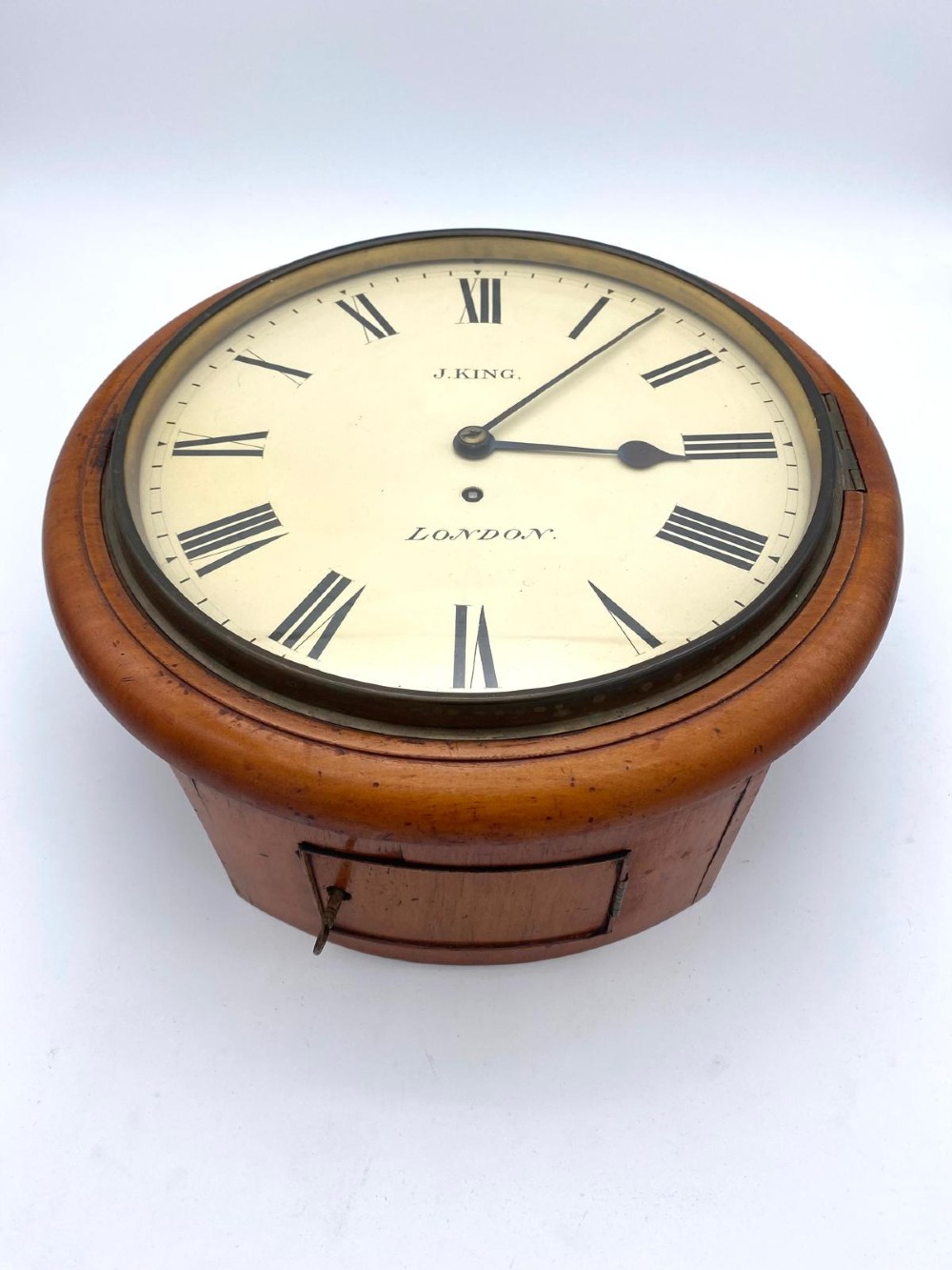 An early Victorian circular mahogany fusee wall clock featuring a cream dial with black Roman numerals and a hinged brass bezel. View II