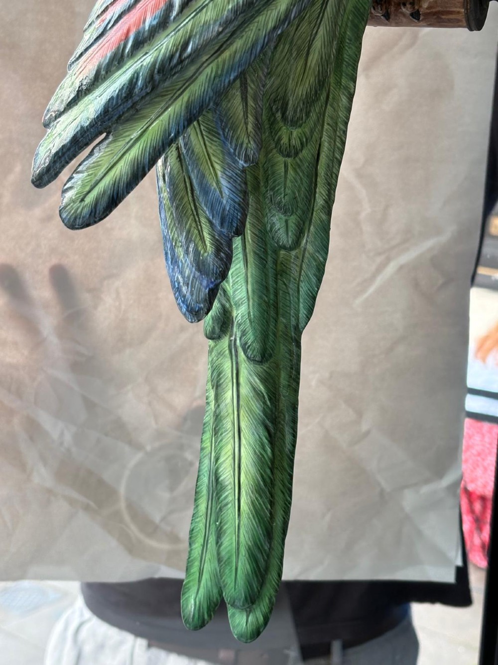 A Victorian green glazed pottery parrot perched on a wooden bar, suspended inside a circular metal hanging hoop. View VII