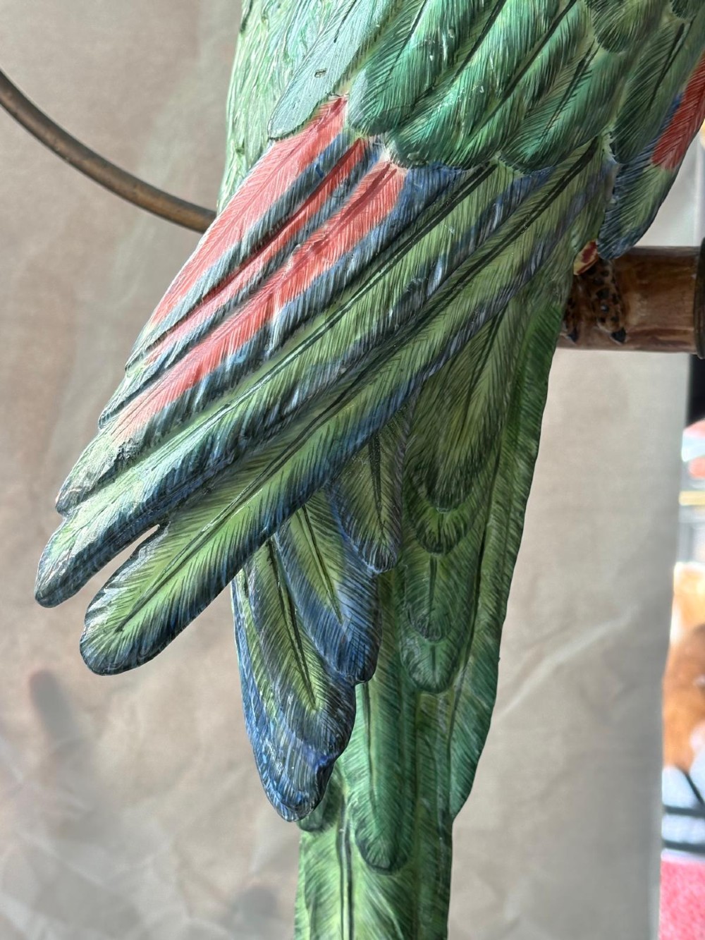A Victorian green glazed pottery parrot perched on a wooden bar, suspended inside a circular metal hanging hoop. View VIII