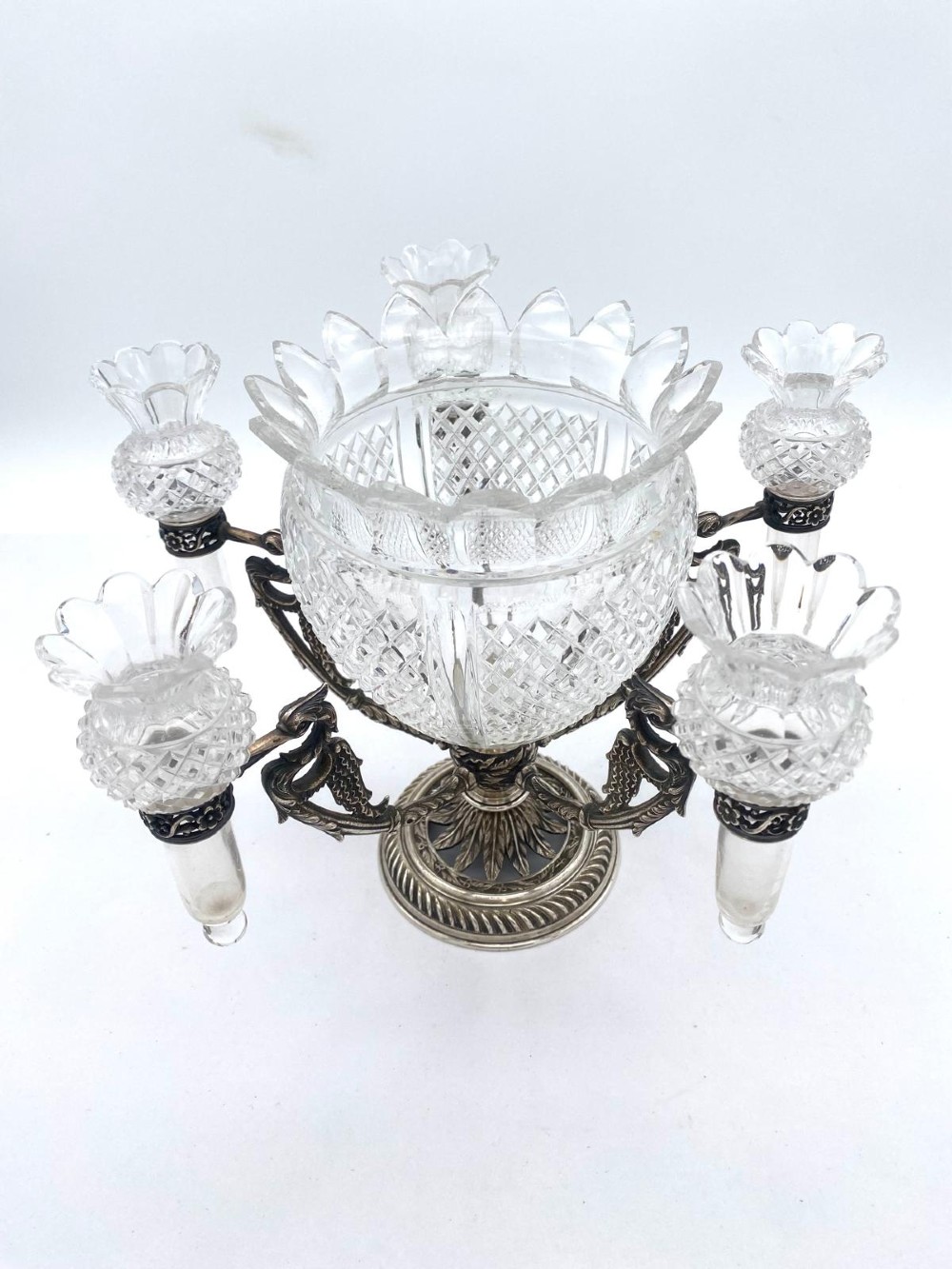 A Victorian cut glass epergne featuring a central diamond-cut bowl surrounded by four smaller glass holders set into silver-plated arms on a round base.