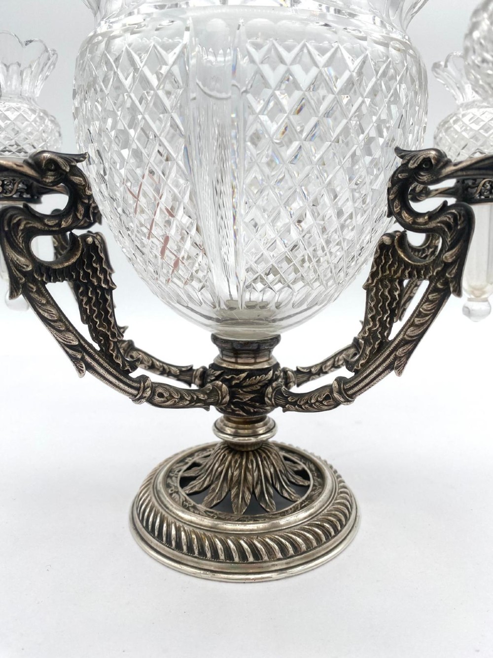 A Victorian cut glass epergne featuring a central diamond-cut bowl surrounded by four smaller glass holders set into silver-plated arms on a round base. View V