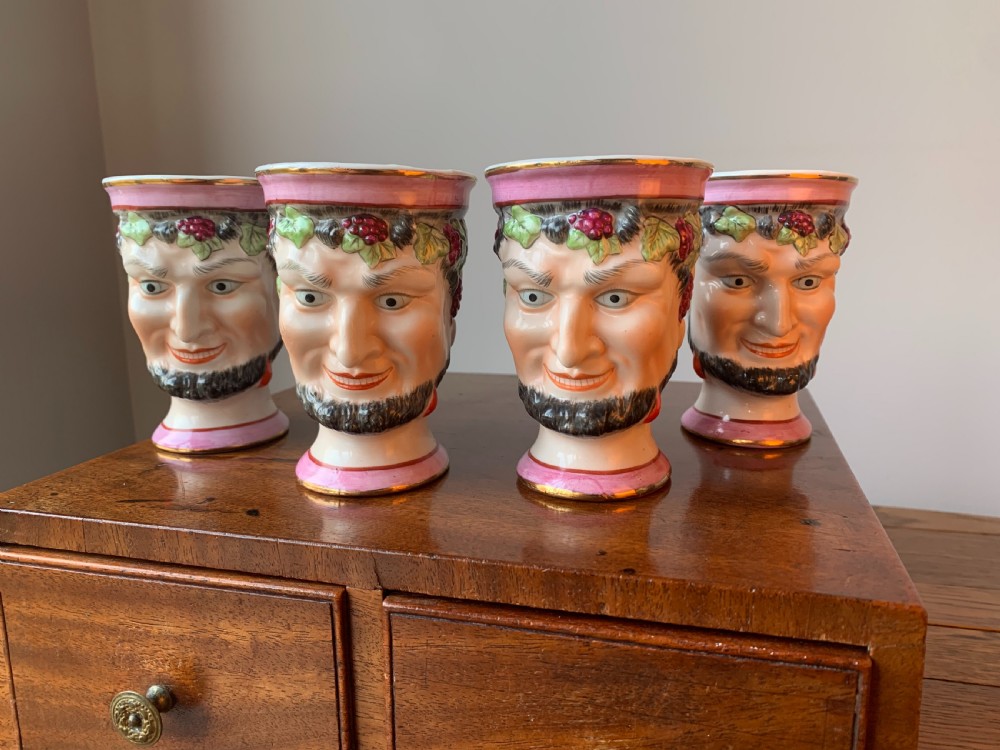 A set of four Victorian Staffordshire ceramic wine cups moulded in the form of bearded satyr faces with grapevine crowns and pink gilded rims. View II