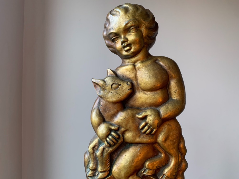 A gilded brass Art Deco sculptural companion set piece depicting a child holding a lamb atop a stepped geometric base. View II