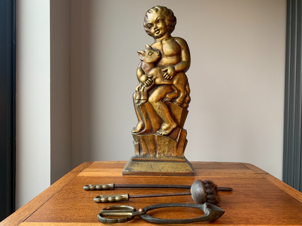 A gilded brass Art Deco sculptural companion set piece depicting a child holding a lamb atop a stepped geometric base. View III