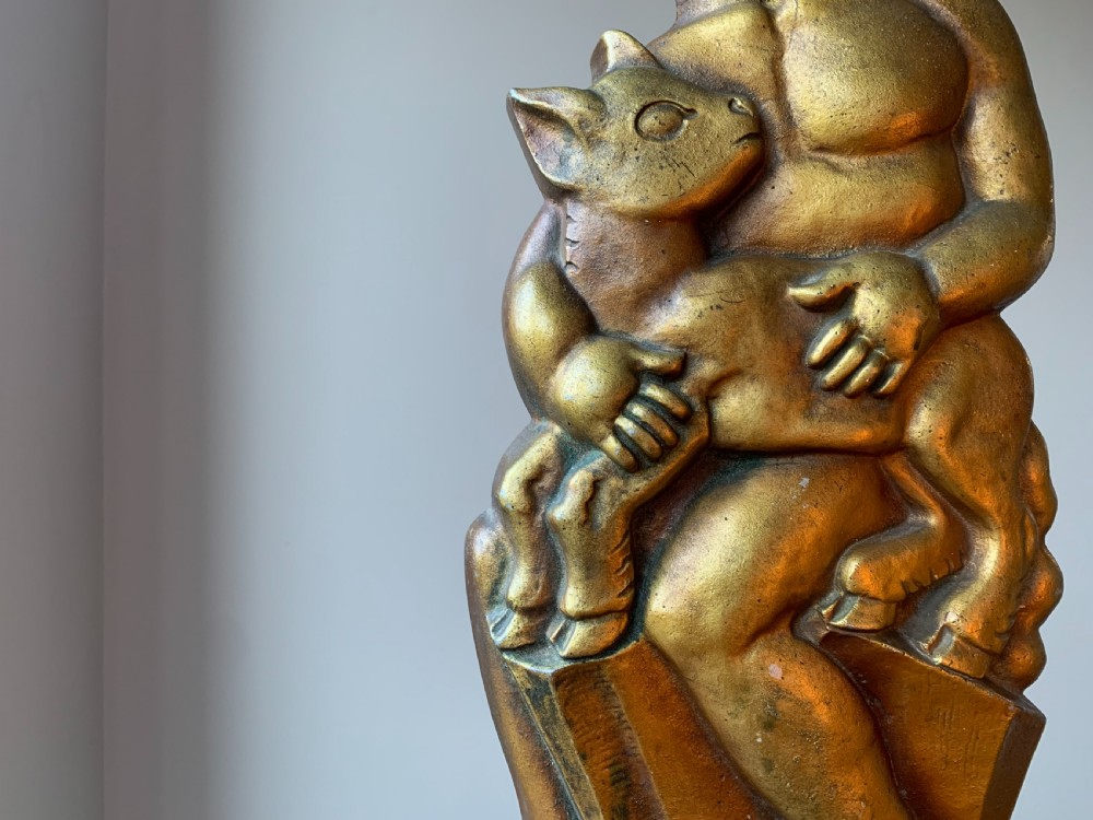 A gilded brass Art Deco sculptural companion set piece depicting a child holding a lamb atop a stepped geometric base. View XI