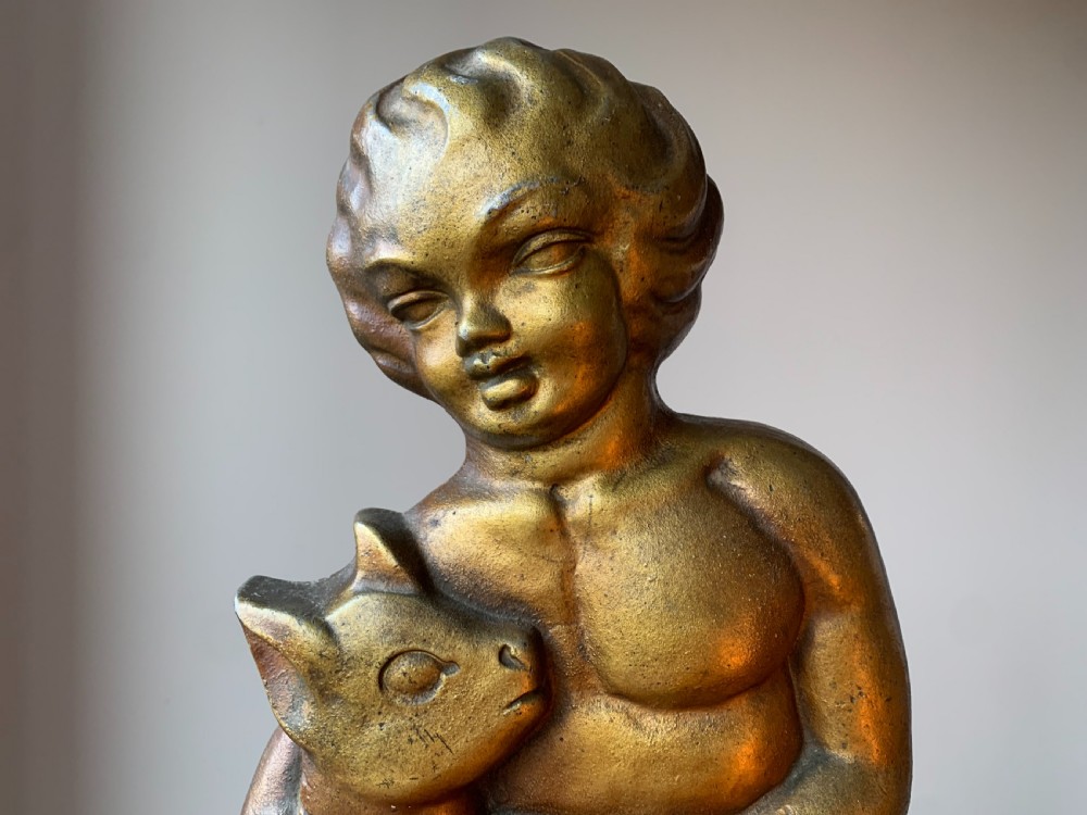 A gilded brass Art Deco sculptural companion set piece depicting a child holding a lamb atop a stepped geometric base. View XIII
