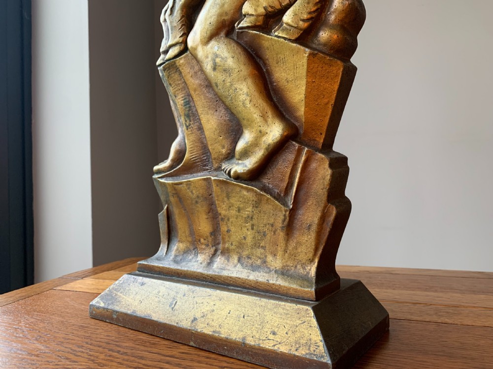 A gilded brass Art Deco sculptural companion set piece depicting a child holding a lamb atop a stepped geometric base. View XXI