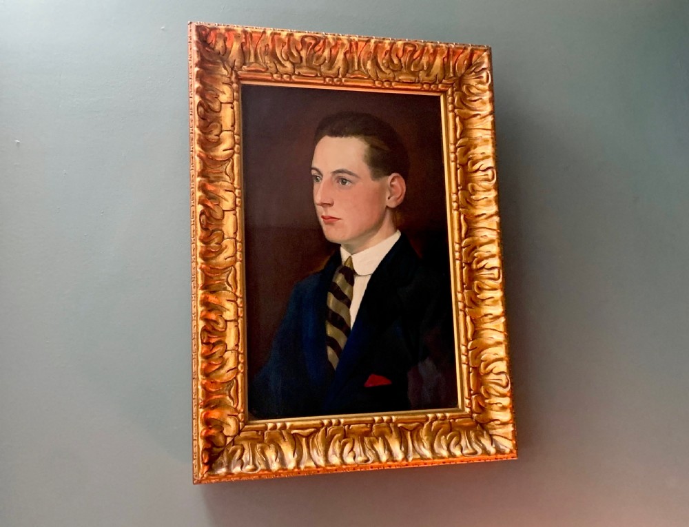 An unsigned Edwardian oil portrait on board depicting a young man in a blue jacket and striped tie, framed within an ornate carved giltwood frame. View VI