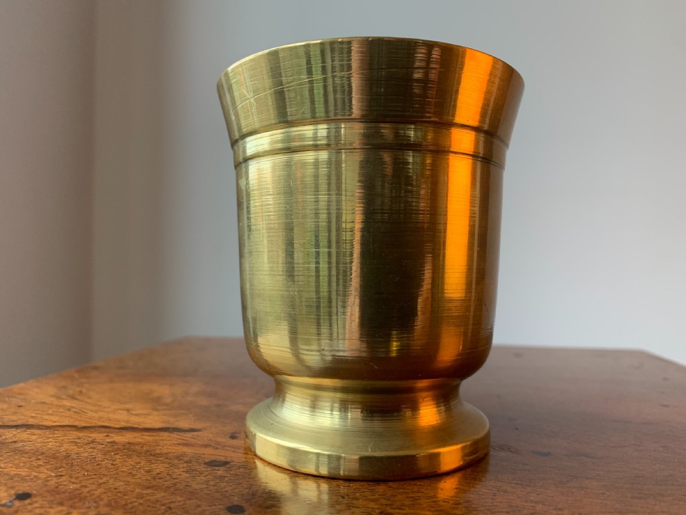 A heavy cast brass mortar with turned incised rings around the body, accompanied by a matching solid brass pestle. View IX