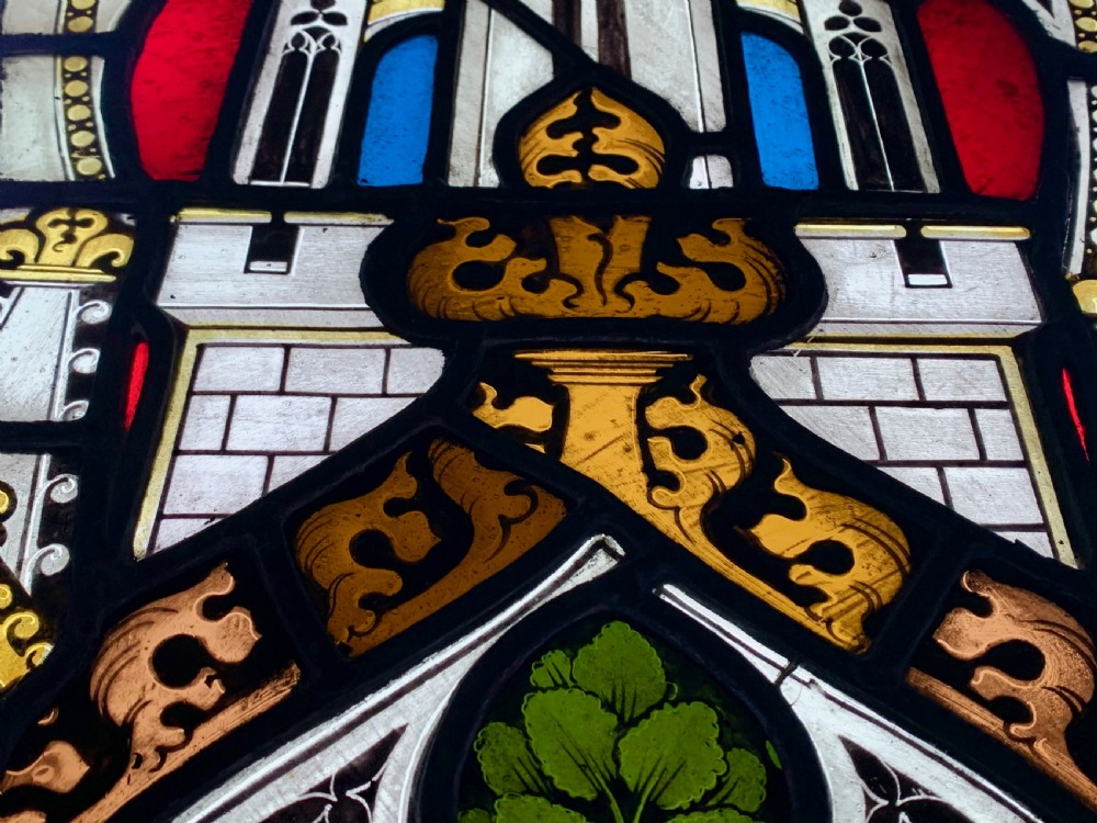 An arched Gothic Revival stained glass panel featuring painted architectural spires, foliate patterns, and lead cames in red, green, yellow, and clear glass. View VII