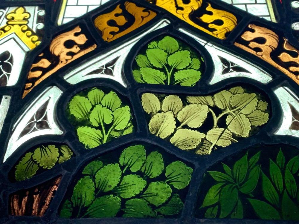 An arched Gothic Revival stained glass panel featuring painted architectural spires, foliate patterns, and lead cames in red, green, yellow, and clear glass. View VIII