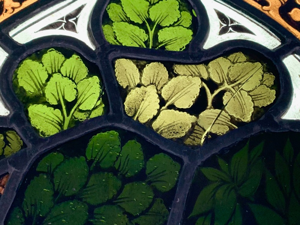 An arched Gothic Revival stained glass panel featuring painted architectural spires, foliate patterns, and lead cames in red, green, yellow, and clear glass. View XIV
