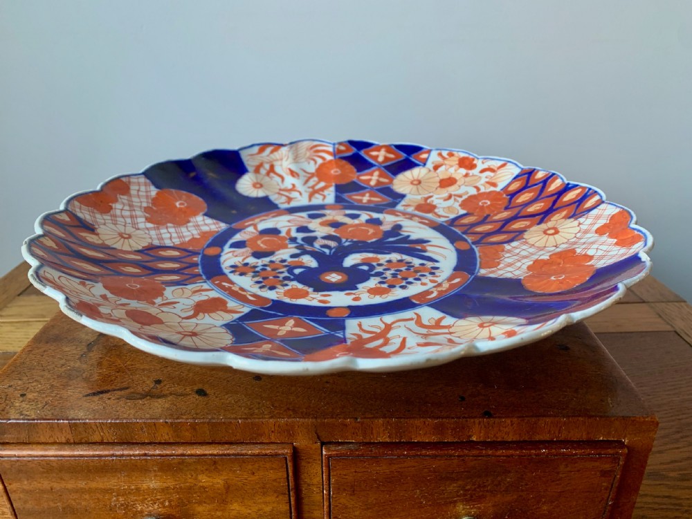 A nineteenth-century Japanese Imari porcelain charger featuring a scalloped rim, hand-painted in cobalt blue and iron-red floral and geometric brocade panels. View III