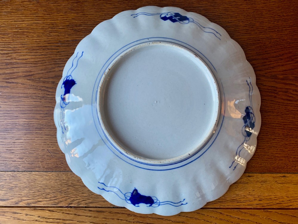 A nineteenth-century Japanese Imari porcelain charger featuring a scalloped rim, hand-painted in cobalt blue and iron-red floral and geometric brocade panels. View IV