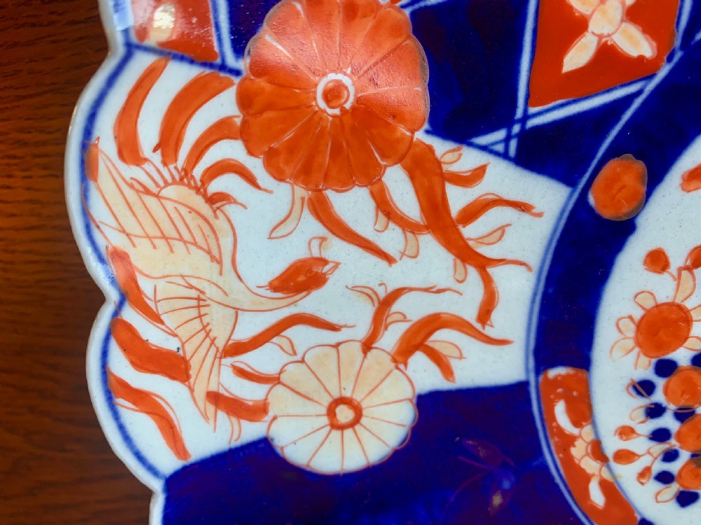 A nineteenth-century Japanese Imari porcelain charger featuring a scalloped rim, hand-painted in cobalt blue and iron-red floral and geometric brocade panels. View VI