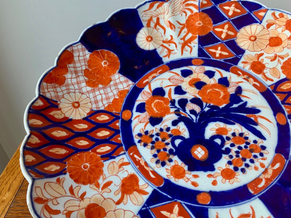 A nineteenth-century Japanese Imari porcelain charger featuring a scalloped rim, hand-painted in cobalt blue and iron-red floral and geometric brocade panels. View XI