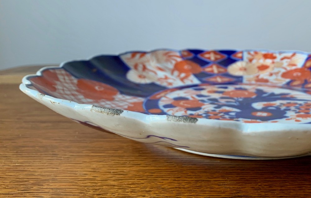 A nineteenth-century Japanese Imari porcelain charger featuring a scalloped rim, hand-painted in cobalt blue and iron-red floral and geometric brocade panels. View XIV