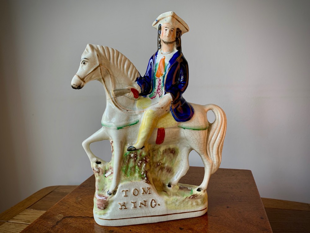 A Victorian Staffordshire pottery flatback figure depicting the highwayman Tom King on horseback wearing a tricorn hat and blue coat.