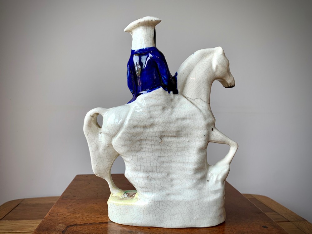 A Victorian Staffordshire pottery flatback figure depicting the highwayman Tom King on horseback wearing a tricorn hat and blue coat. View V