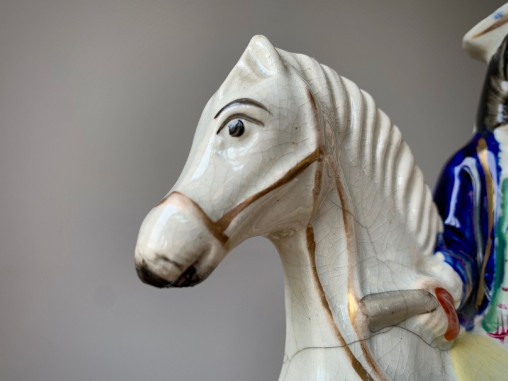 A Victorian Staffordshire pottery flatback figure depicting the highwayman Tom King on horseback wearing a tricorn hat and blue coat. View VIII