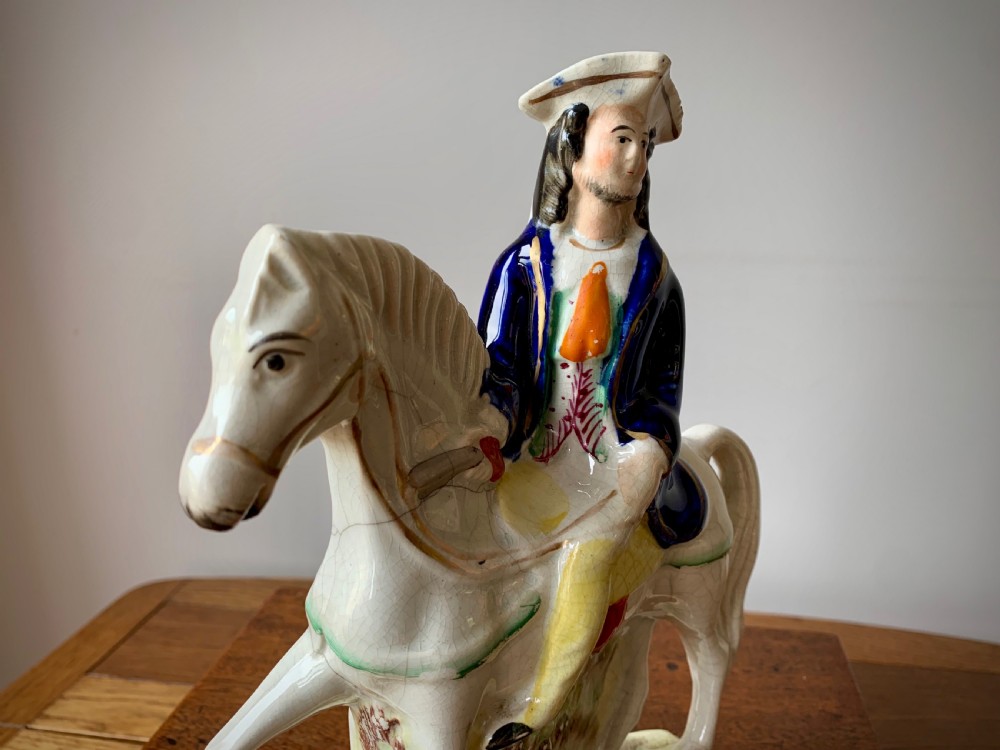 A Victorian Staffordshire pottery flatback figure depicting the highwayman Tom King on horseback wearing a tricorn hat and blue coat. View XII