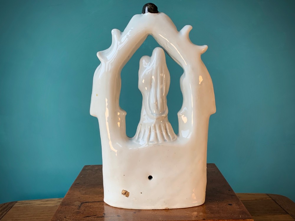 An antique Staffordshire earthenware holy water stoup with figures of the Madonna and Child under an arch flanked by angels in cream glaze with blue and brown painted details. View II
