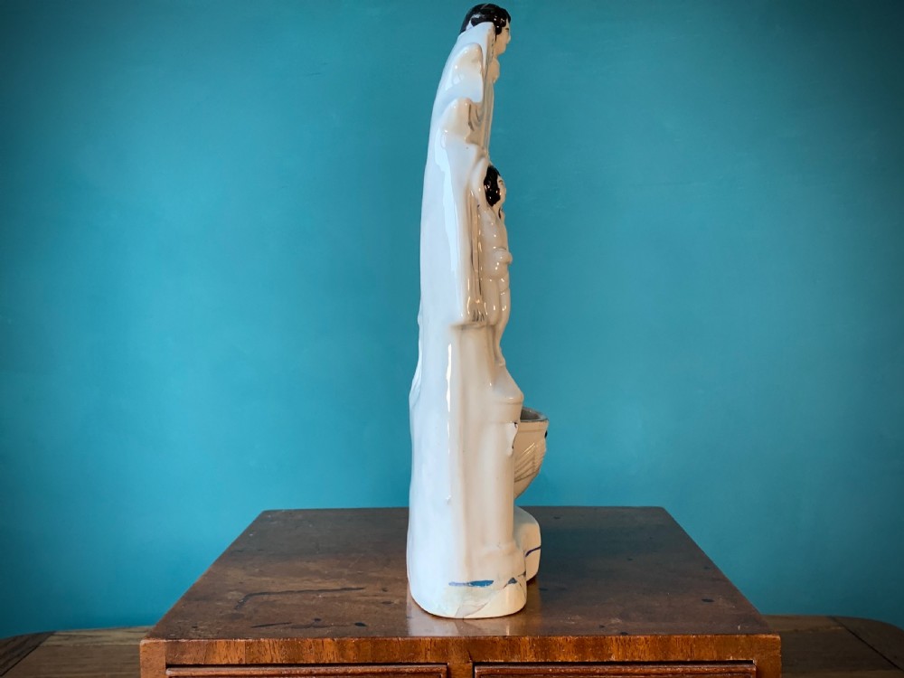 An antique Staffordshire earthenware holy water stoup with figures of the Madonna and Child under an arch flanked by angels in cream glaze with blue and brown painted details. View III