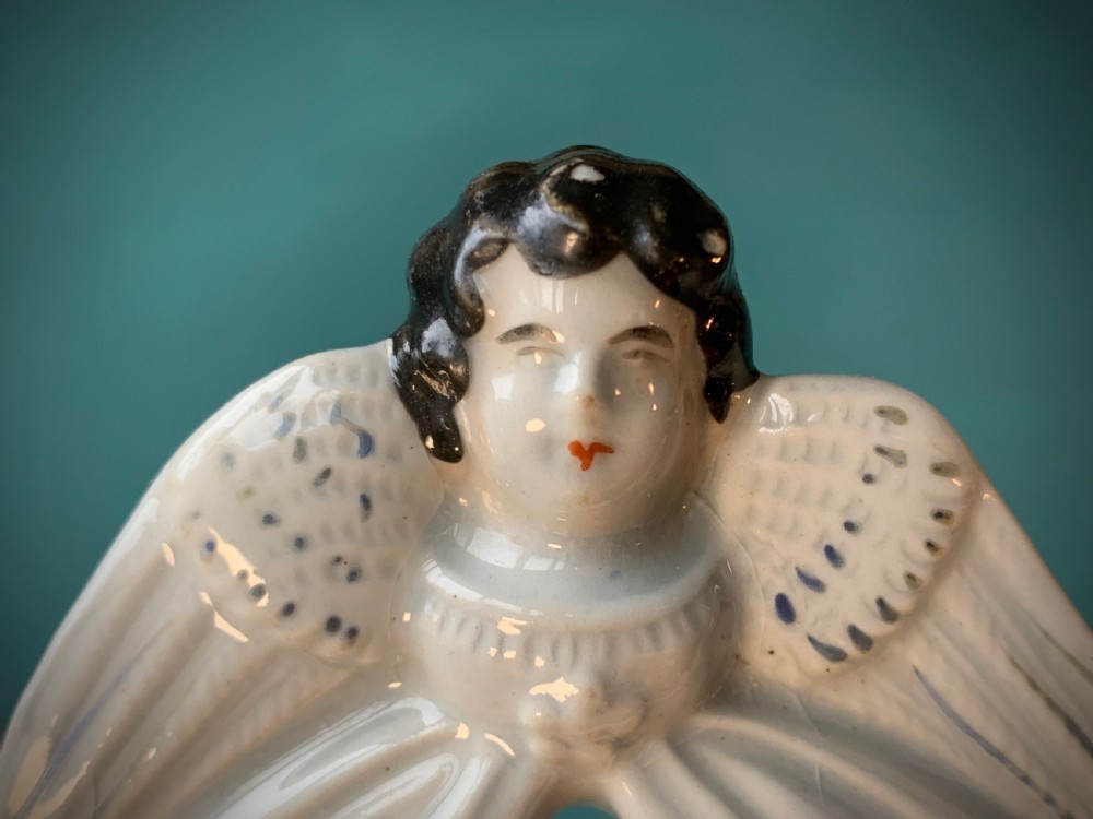 An antique Staffordshire earthenware holy water stoup with figures of the Madonna and Child under an arch flanked by angels in cream glaze with blue and brown painted details. View VI