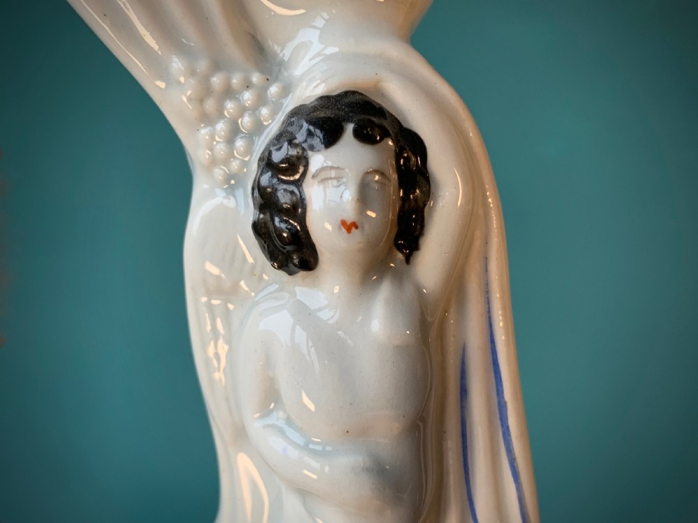An antique Staffordshire earthenware holy water stoup with figures of the Madonna and Child under an arch flanked by angels in cream glaze with blue and brown painted details. View XI