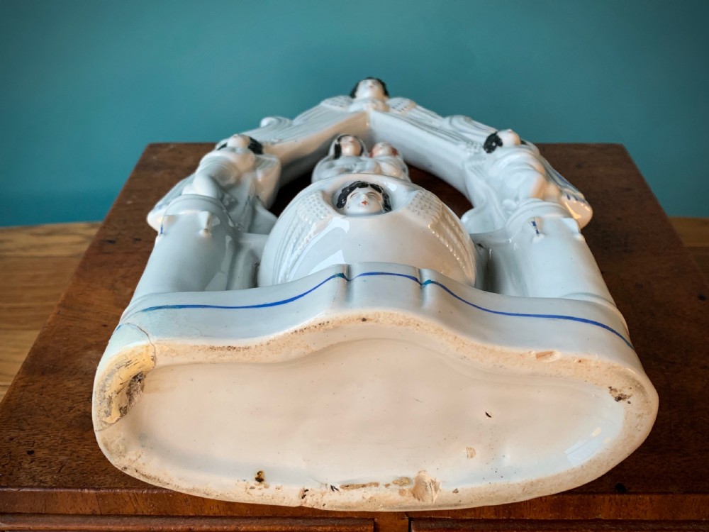 An antique Staffordshire earthenware holy water stoup with figures of the Madonna and Child under an arch flanked by angels in cream glaze with blue and brown painted details. View XIV