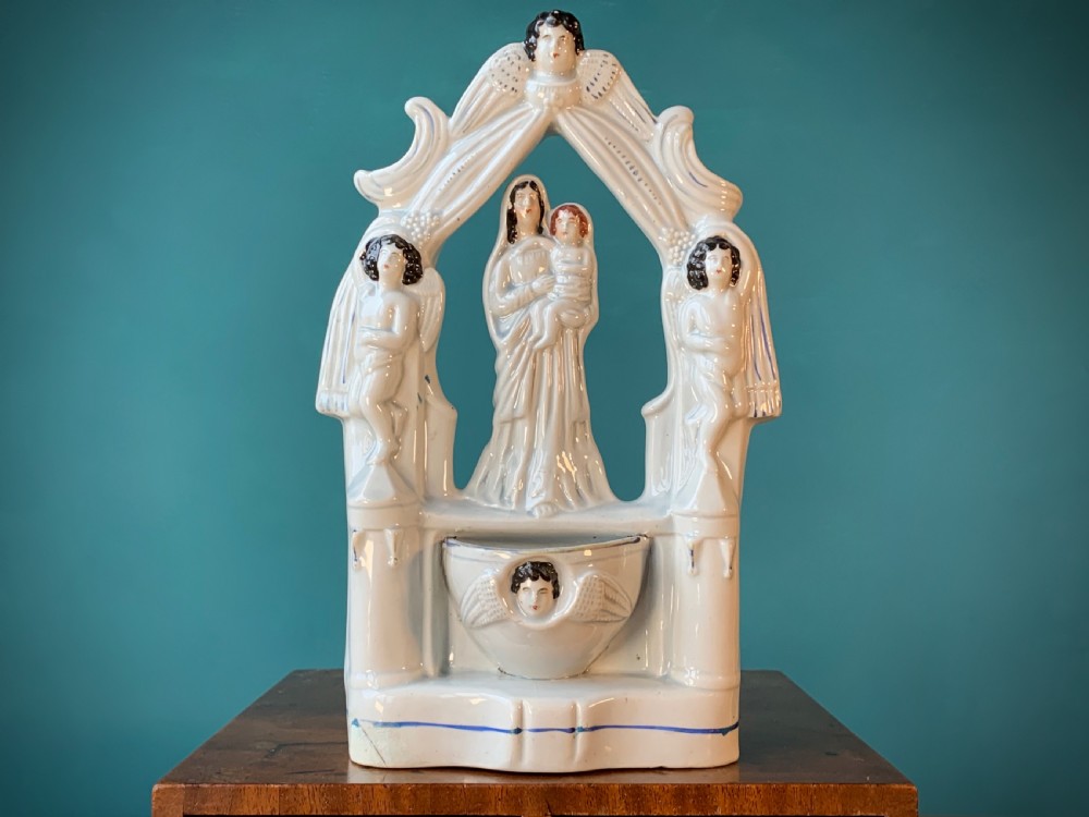 An antique Staffordshire earthenware holy water stoup with figures of the Madonna and Child under an arch flanked by angels in cream glaze with blue and brown painted details. View XV