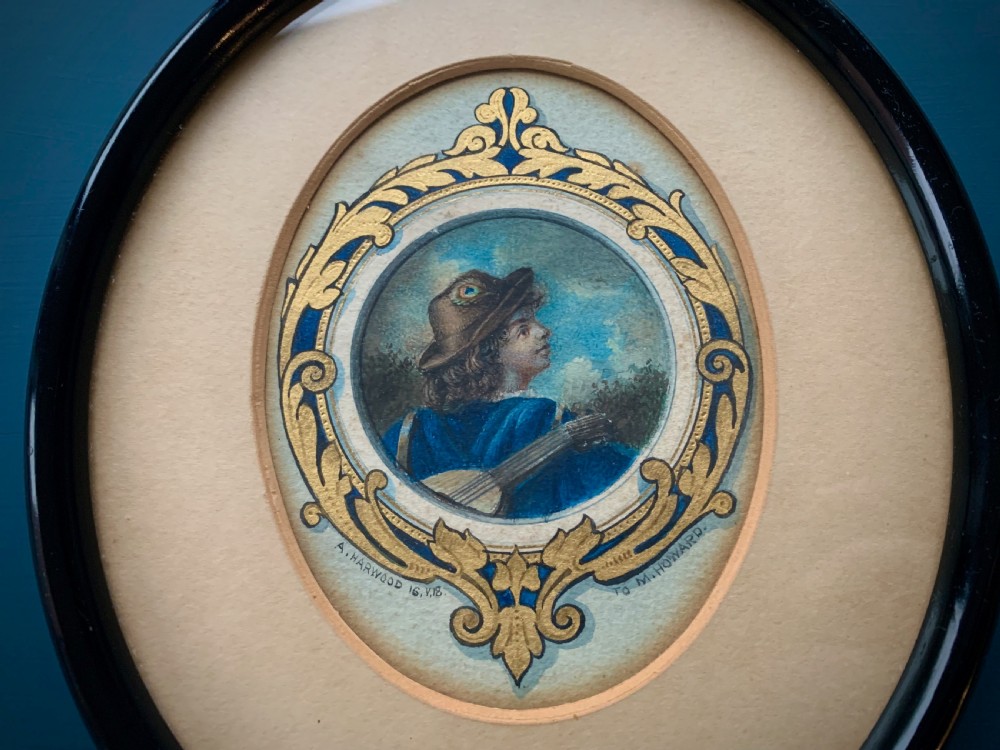An oval framed miniature watercolour painting depicting a travelling musician wearing a blue tunic and feathered hat, surrounded by an ornate gilded and blue cartouche border. View IV