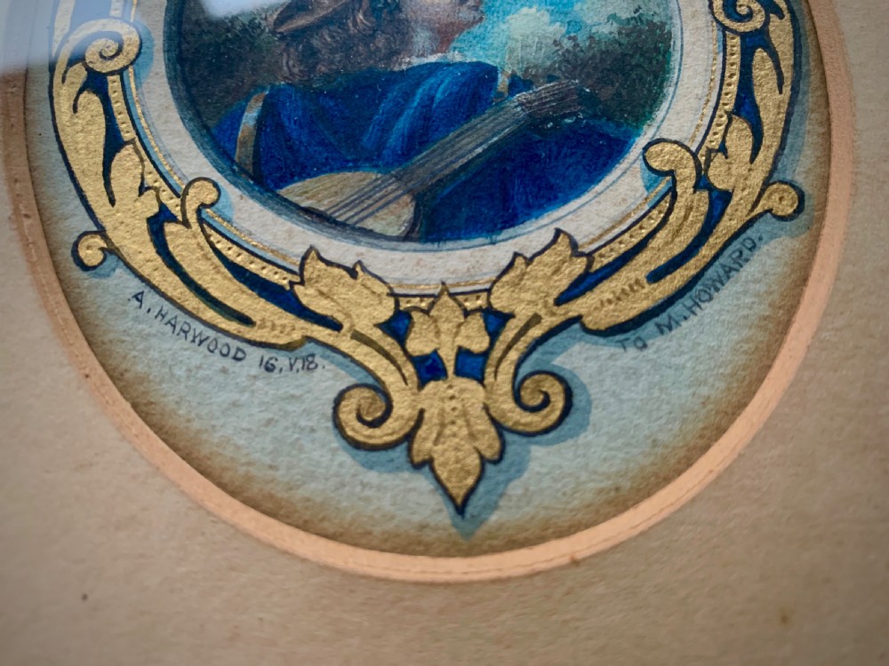 An oval framed miniature watercolour painting depicting a travelling musician wearing a blue tunic and feathered hat, surrounded by an ornate gilded and blue cartouche border. View V
