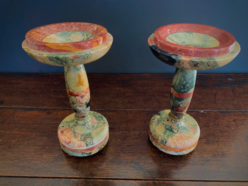 A pair of turned, variegated marble tazzas featuring shallow circular dishes raised on baluster stems and round bases in shades of red, green, and tan.
