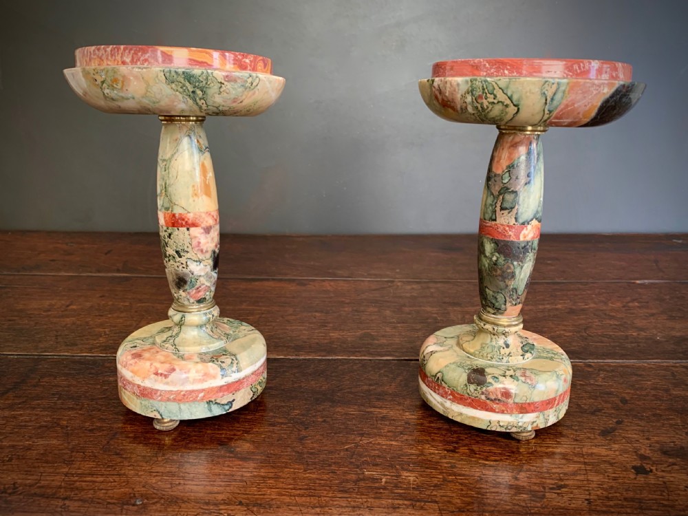 A pair of turned, variegated marble tazzas featuring shallow circular dishes raised on baluster stems and round bases in shades of red, green, and tan. View XIX