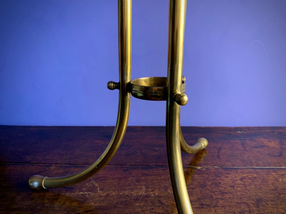 A Victorian tubular brass magazine stand featuring mesh wire compartments, a central carrying handle, and a mahogany base supported by splayed legs. View XI