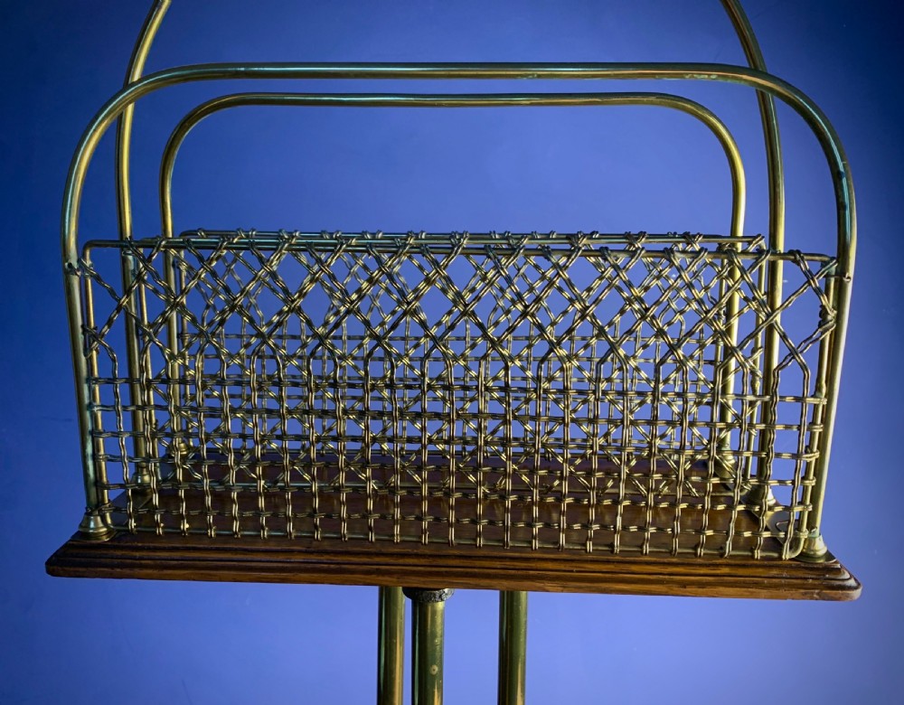 A Victorian tubular brass magazine stand featuring mesh wire compartments, a central carrying handle, and a mahogany base supported by splayed legs. View XII